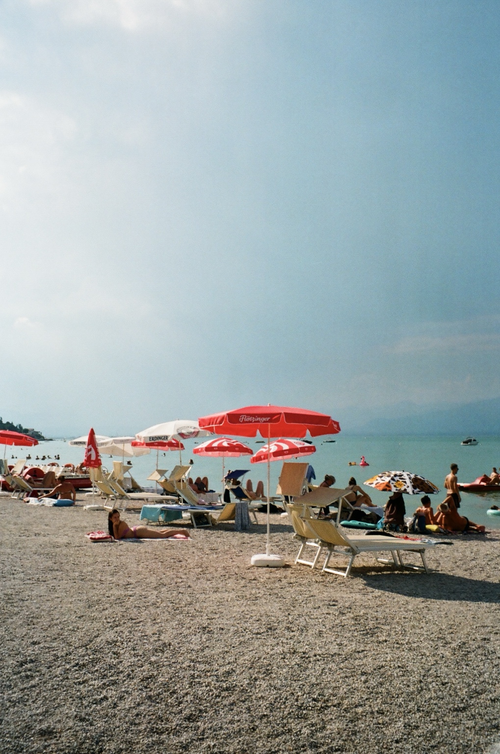 Red and white umbrellas along a lakeside beach