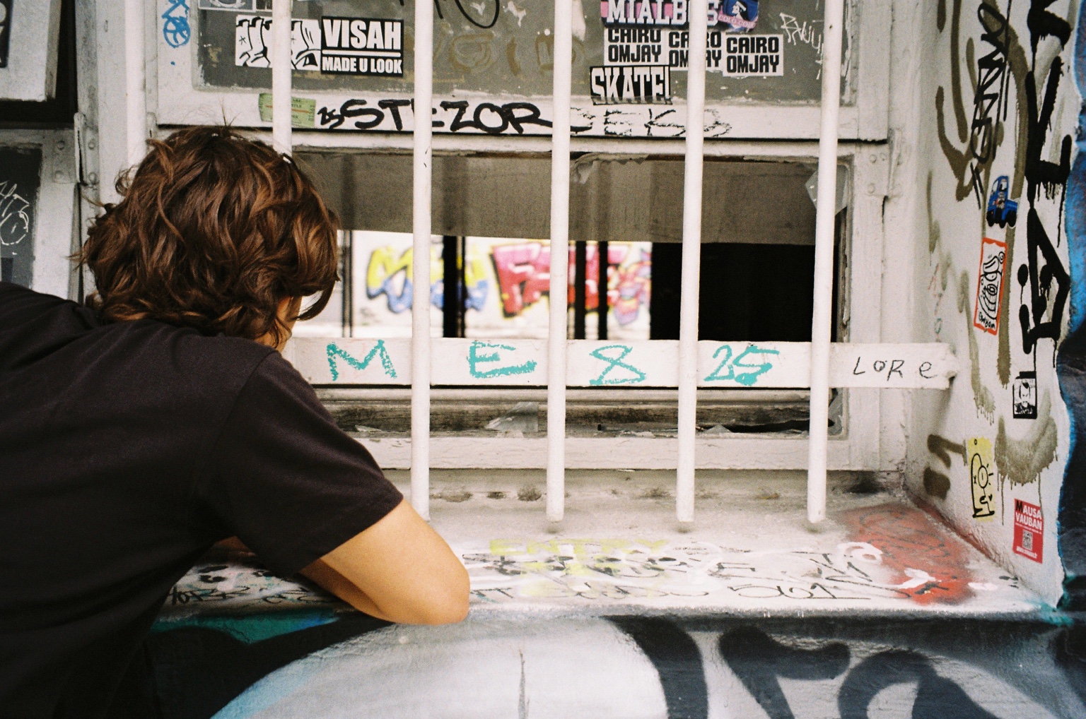 Person leaning beside a graffiti-covered window